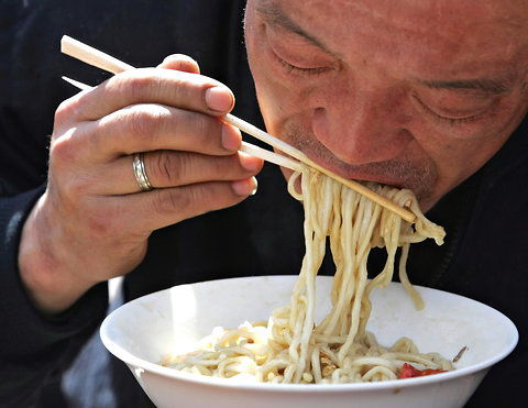 北京的一家餐馆,一名男子正用一次性筷子吃面.